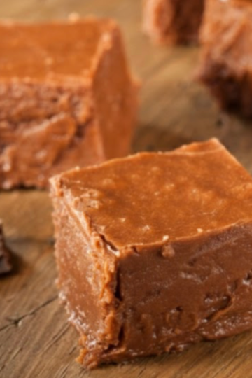 Close-up of creamy old-fashioned chocolate fudge cut into smooth squares on a cutting board.