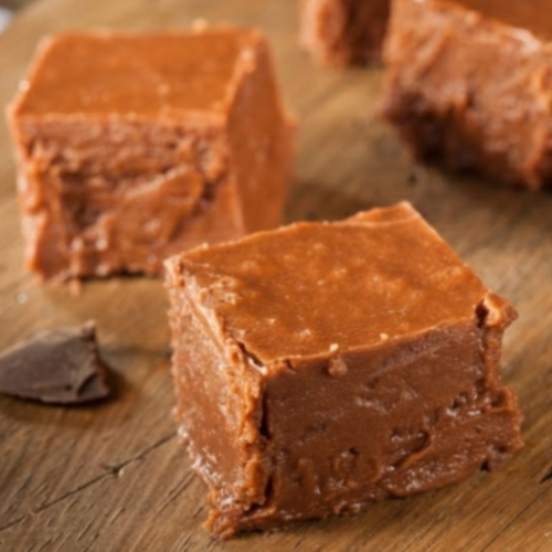 Close-up of creamy old-fashioned chocolate fudge cut into smooth squares on a cutting board.