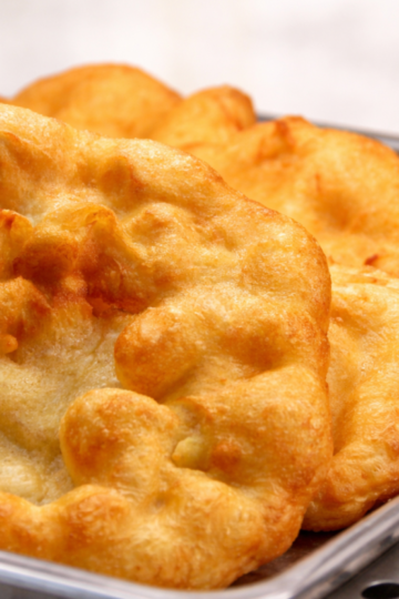 A piece of traditional Indian fry bread, golden brown and fluffy, fried to perfection.