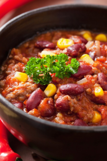 A large bowl of quick and hearty chili soup, garnished with a dollop of sour cream, shredded cheese and fresh cilantro.