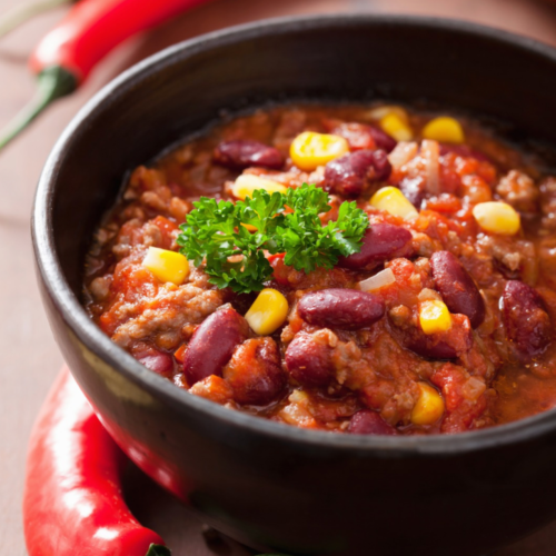 A large bowl of quick and hearty chili soup, garnished with a dollop of sour cream, shredded cheese and fresh cilantro.
