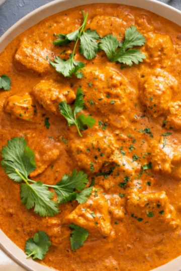 A bowl of creamy authentic Indian butter, chicken, garnished with fresh cilantro.