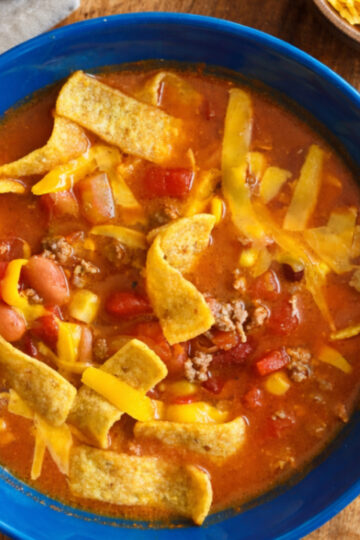 A hearty bowl of homemade chili filled with tender ground meat, beans, and a rich tomato-based sauce, garnished with corn chips.
