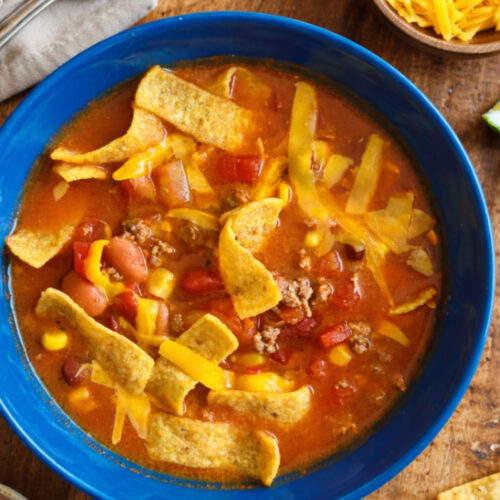 A hearty bowl of homemade chili filled with tender ground meat, beans, and a rich tomato-based sauce, garnished with corn chips.