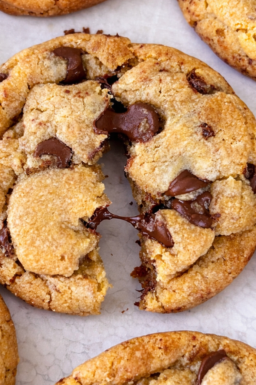 Thick and soft brown butter chocolate chip cookies with golden edges and melty chocolate chips stacked on a counter.