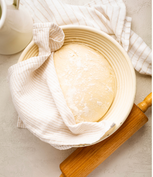 A perfectly fluffy ball of quick rising pizza dough in a rising bowl.