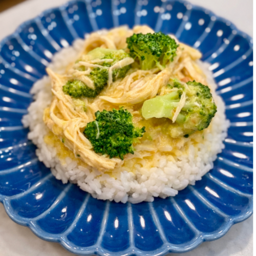 Easy Instant Pot chicken and broccoli served over white rice on a blue plate with a creamy sauce.