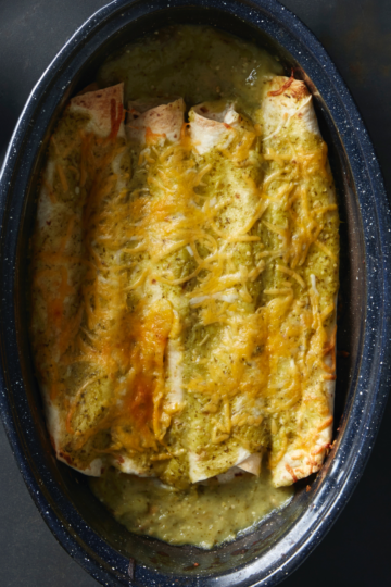 Baked gluten-free chicken, enchiladas, covered in green sauce and melted cheese in a casserole dish