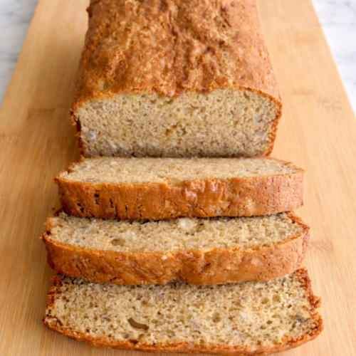 Slices of moist banana bread with a golden-brown crust, served on a white plate with a soft, tender crumb visible.