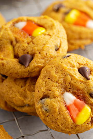 A stack of three super soft pumpkin chocolate chip cookies on a cooling rack.
