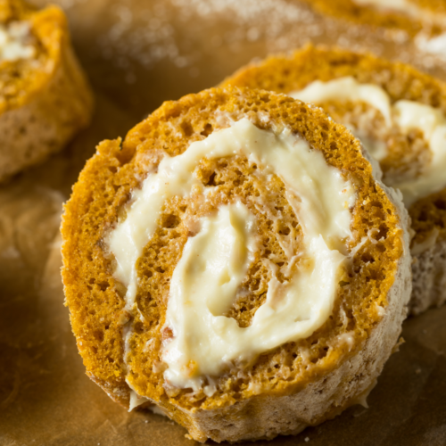 Brown Butter Pumpkin Roll with Maple Cream Filling dusted with powdered sugar and drizzled with maple syrup