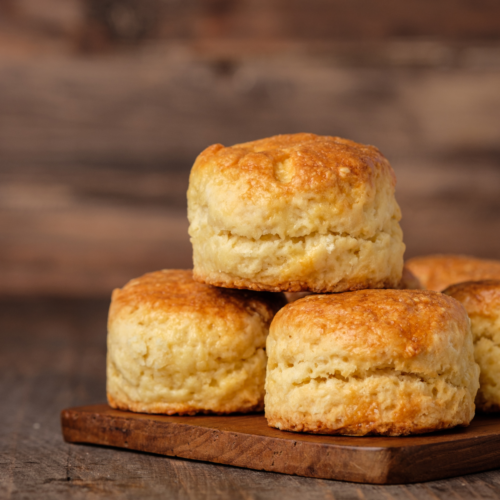 Freshly baked brown butter honey glazed biscuits on a cutting board, dripping with golden honey and melted butter