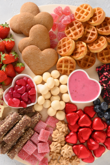 Dessert charcuterie board with cookies, chocolate, fruit, and sweet treats arranged on a serving board for a party.