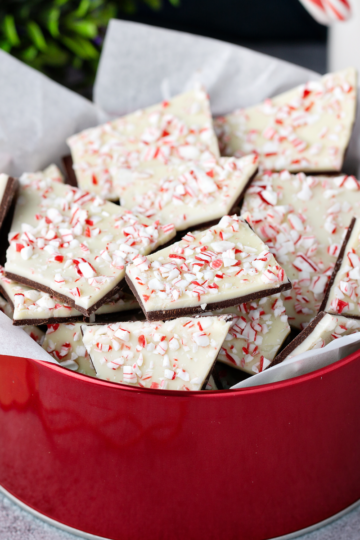 Peppermint bark pieces in a red tin with crushed candy canes, showing portion sizes for a peppermint bark calculator