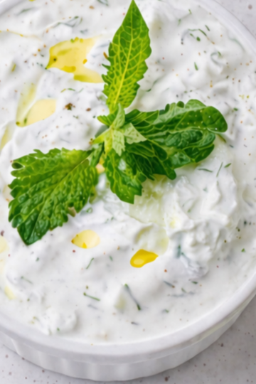 A bowl of creamy homemade garlic ranch dip topped with fresh herbs, surrounded by crisp vegetables for dipping.