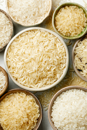 A bowl of white rice with a spoon of coconut oil beside it, representing the coconut oil and freezing method to lower rice calories.