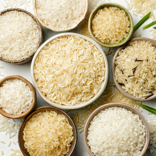 A bowl of white rice with a spoon of coconut oil beside it, representing the coconut oil and freezing method to lower rice calories.