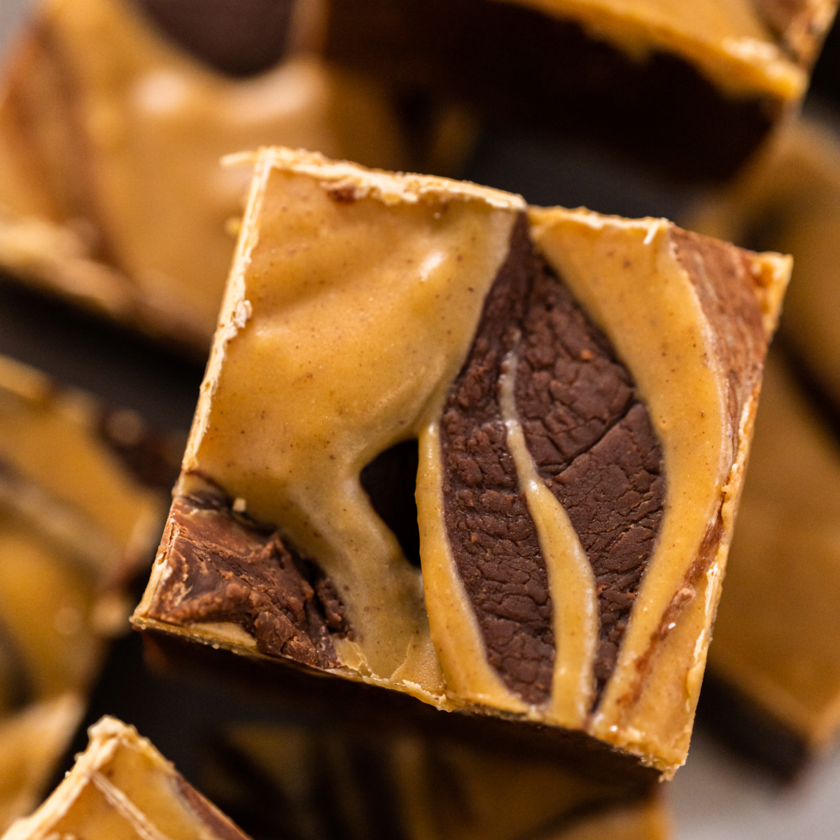 Close-up of a thick square of chocolate and peanut butter swirl fudge with a glossy marbled top and dense, creamy texture.