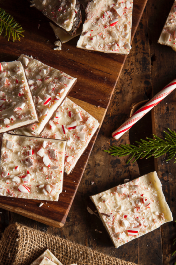 Large pile of homemade white and dark chocolate peppermint bark broken into festive pieces, ready for serving to a holiday crowd.