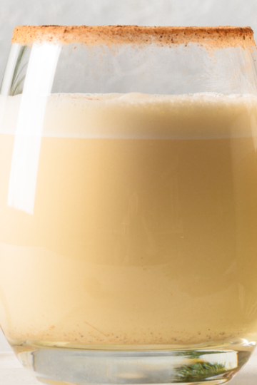 Homemade non-alcoholic eggnog in a glass topped with nutmeg around the rim of the glass.