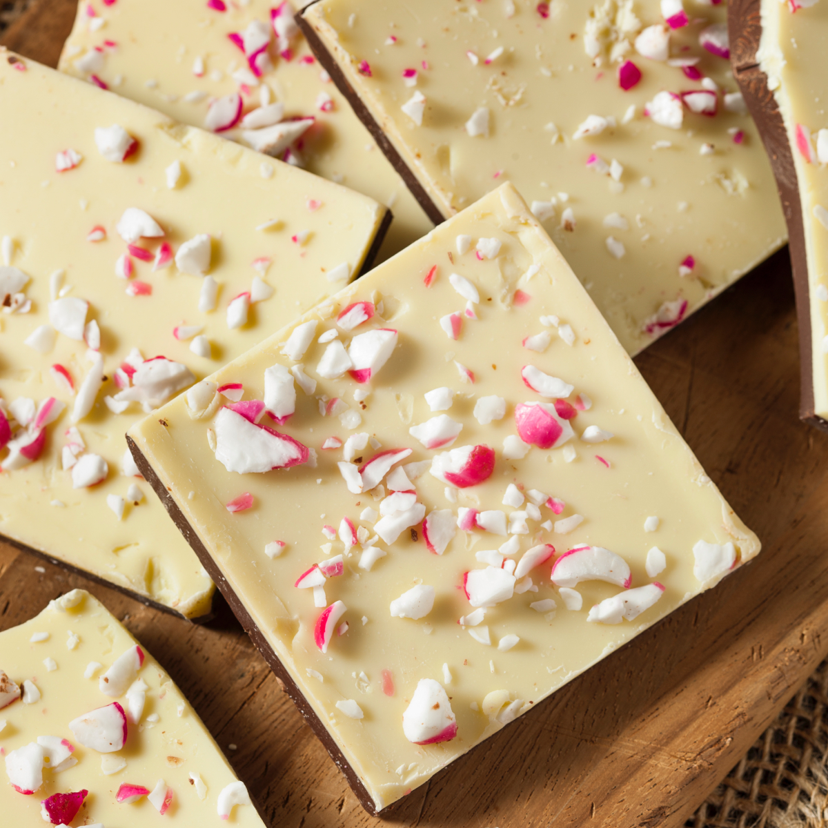 Large pile of homemade white and dark chocolate peppermint bark broken into festive pieces, ready for serving to a holiday crowd.
