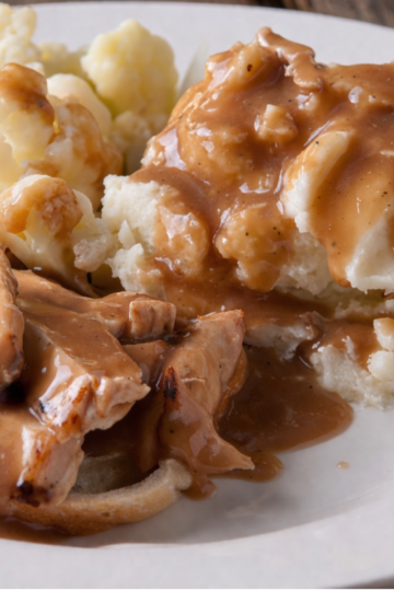 Gluten free sourdough discard gravy on mashed potatoes , smooth and creamy with a rich golden-brown color.