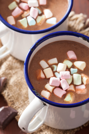 Large mug of rich homemade hot chocolate topped with colorful marshmallows on a cozy winter table.