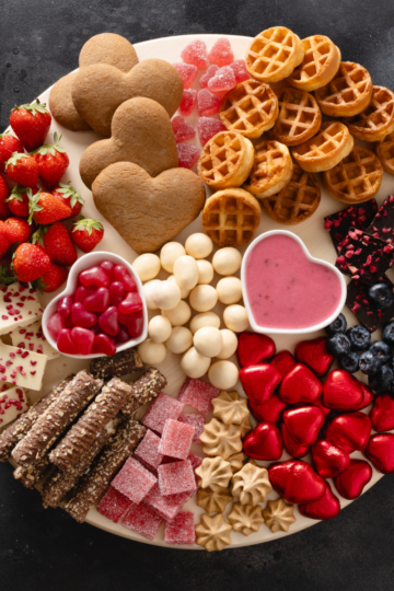 The ultimate dessert, charcuterie, board with cookies, brownies, fruit, chocolate, and dipping sauces on a wooden platter.