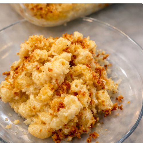 Creamy smoked gouda mac and cheese topped with golden, crispy breadcrumbs, served on a clear plate with rich, cheesy sauce.