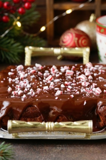Fudgy peppermint hot chocolate brownies topped with silky chocolate ganache and crushed candy canes on a holiday baking tray.