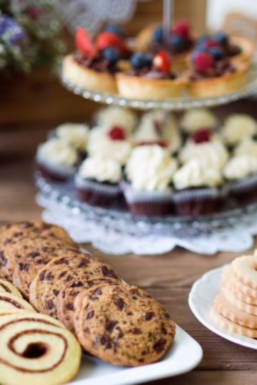 Assorted holiday cookies arranged on a platter with festive decorations, showing a variety of shapes, colors, and textures for a Christmas cookie exchange.