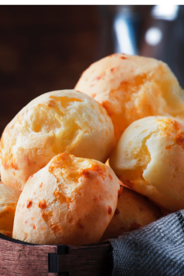 Soft, golden Brazilian cheese bread rolls baked without tapioca flour, showing a fluffy interior and melted cheese throughout in a warm basket.