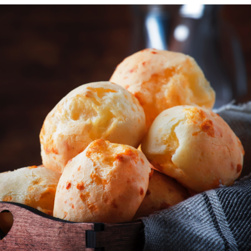 Soft, golden Brazilian cheese bread rolls baked without tapioca flour, showing a fluffy interior and melted cheese throughout in a warm basket.