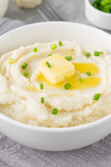 How much mashed potatoes to make per person chart on a holiday table with creamy mashed potatoes in a serving bowl.