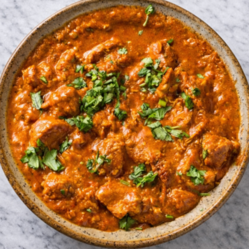 Creamy restaurant-style chicken tikka masala in a dish, featuring tender marinated chicken pieces coated in a rich tomato-cream sauce with cilantro on top.