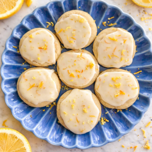 Frosted citrus cookies topped with a crackly orange glaze and fresh citrus zest on a serving dish.