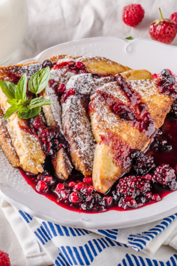 A plate filled with French toast covered with a beautiful berry syrup.
