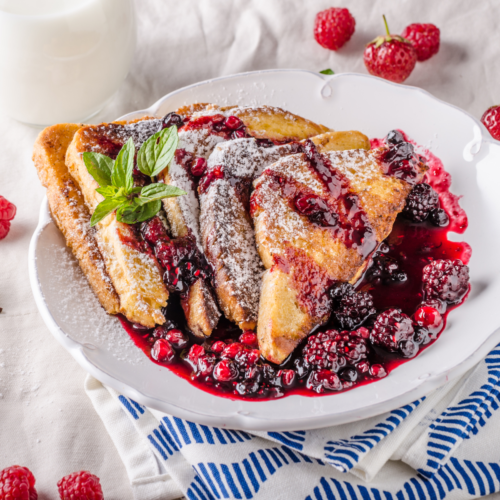 A plate filled with French toast covered with a beautiful berry syrup.