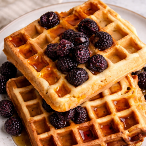 Crispy sourdough discard waffles made with brown butter, golden and airy with crisp edges, resting on a wooden surface.