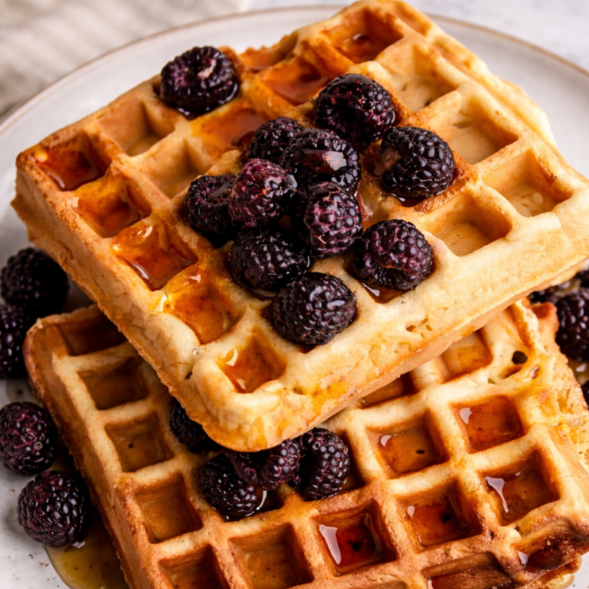 Crispy sourdough discard waffles made with brown butter, golden and airy with crisp edges, resting on a wooden surface.