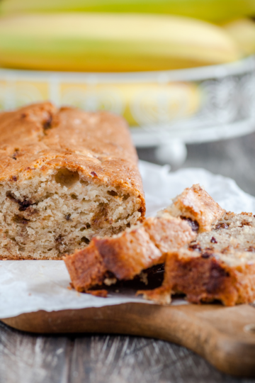 “Freshly baked banana bread sitting on a kitchen counter, showing soft, moist texture and golden crumb.