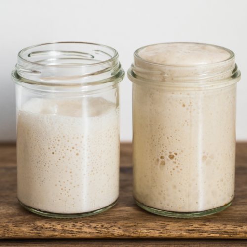 A bubbly sourdough starter in a clear jar showing fermentation activity, used to illustrate baking science, feeding ratios, and troubleshooting starter issues.