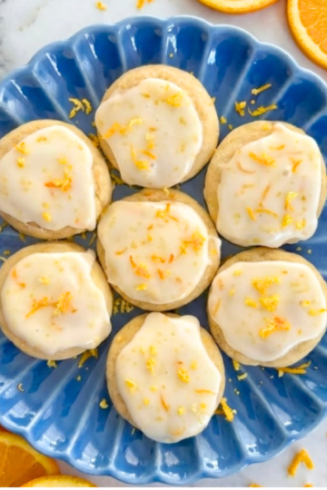 Frosted citrus cookies topped with a crackly orange glaze and fresh citrus zest on a serving dish.
