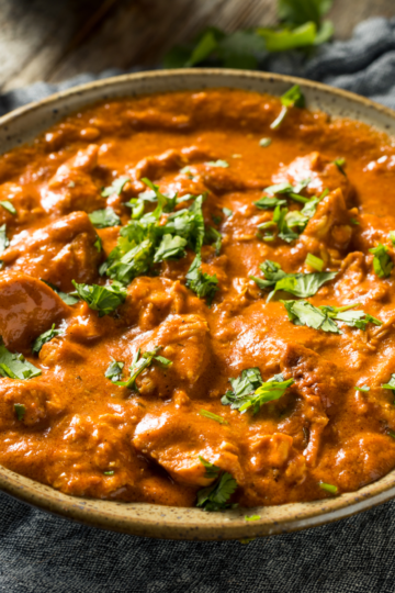 Creamy restaurant-style chicken tikka masala in a dish, featuring tender marinated chicken pieces coated in a rich tomato-cream sauce with cilantro on top.