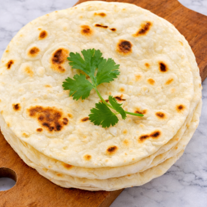 Soft homemade naan bread cooked in a skillet and ready to be brushed with butter.