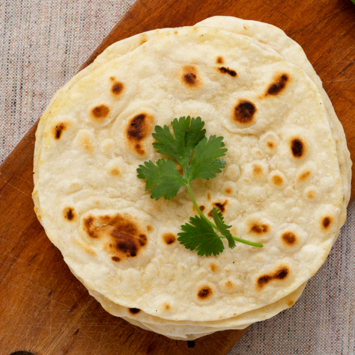 Soft homemade naan bread cooked in a skillet and ready to be brushed with butter.