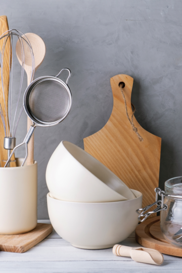 Mixing utensils, cutting boards and mixing bowls in a well lit kitchen.