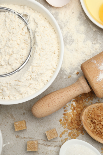 A kitchen counter filled with baking essentials like butter, flour, milk and sugar.