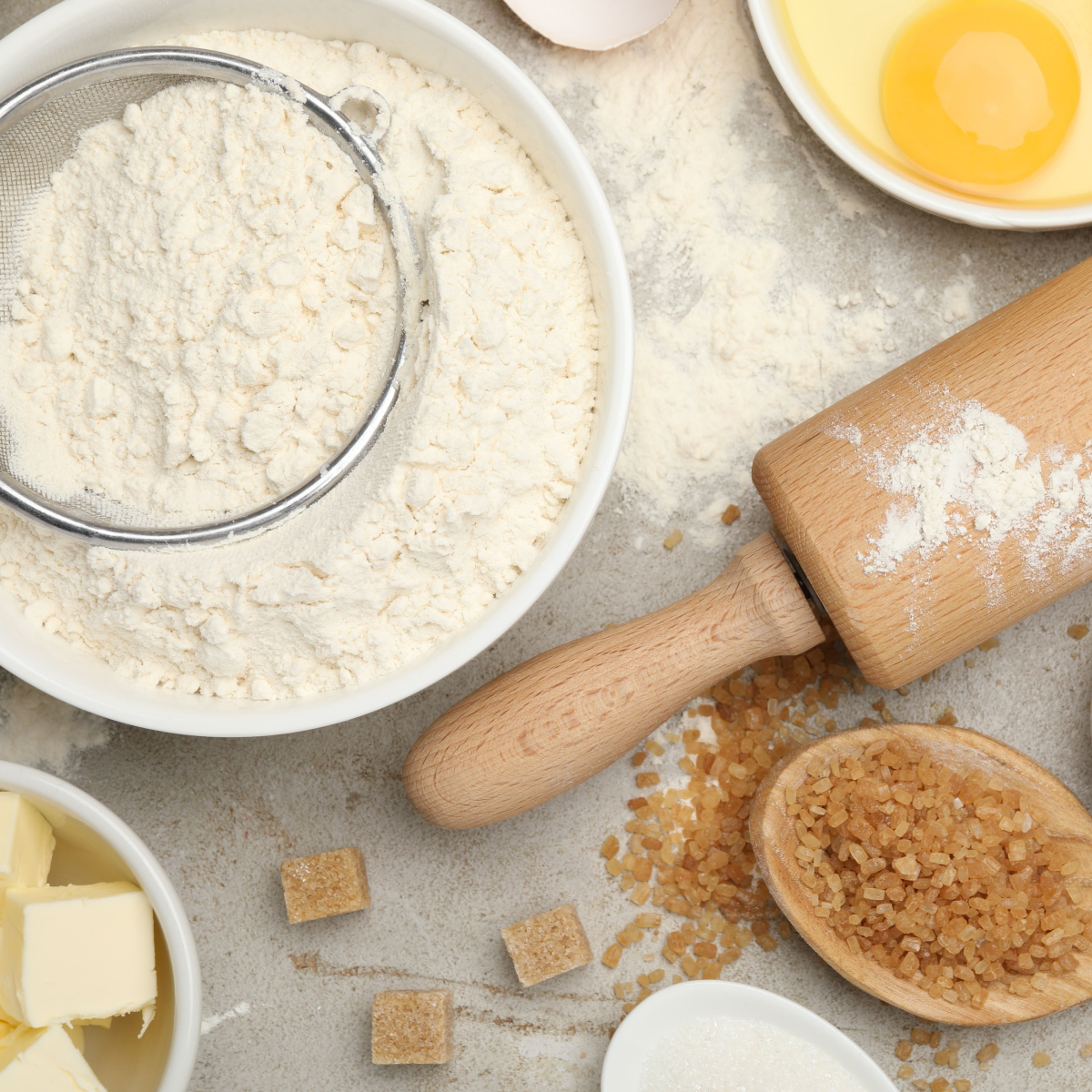 A kitchen counter filled with baking essentials like butter, flour, milk and sugar.