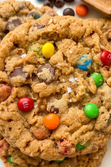 Brown butter monster cookies with chocolate chips, oats, and M&M candies on a white plate